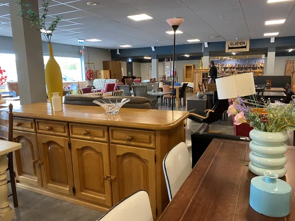 Winkelvloer met houten meubels, serviesgoed en decoraties in een kringloopwinkel