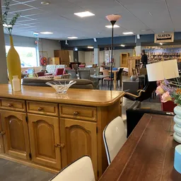 Winkelvloer met houten meubels, serviesgoed en decoraties in een kringloopwinkel