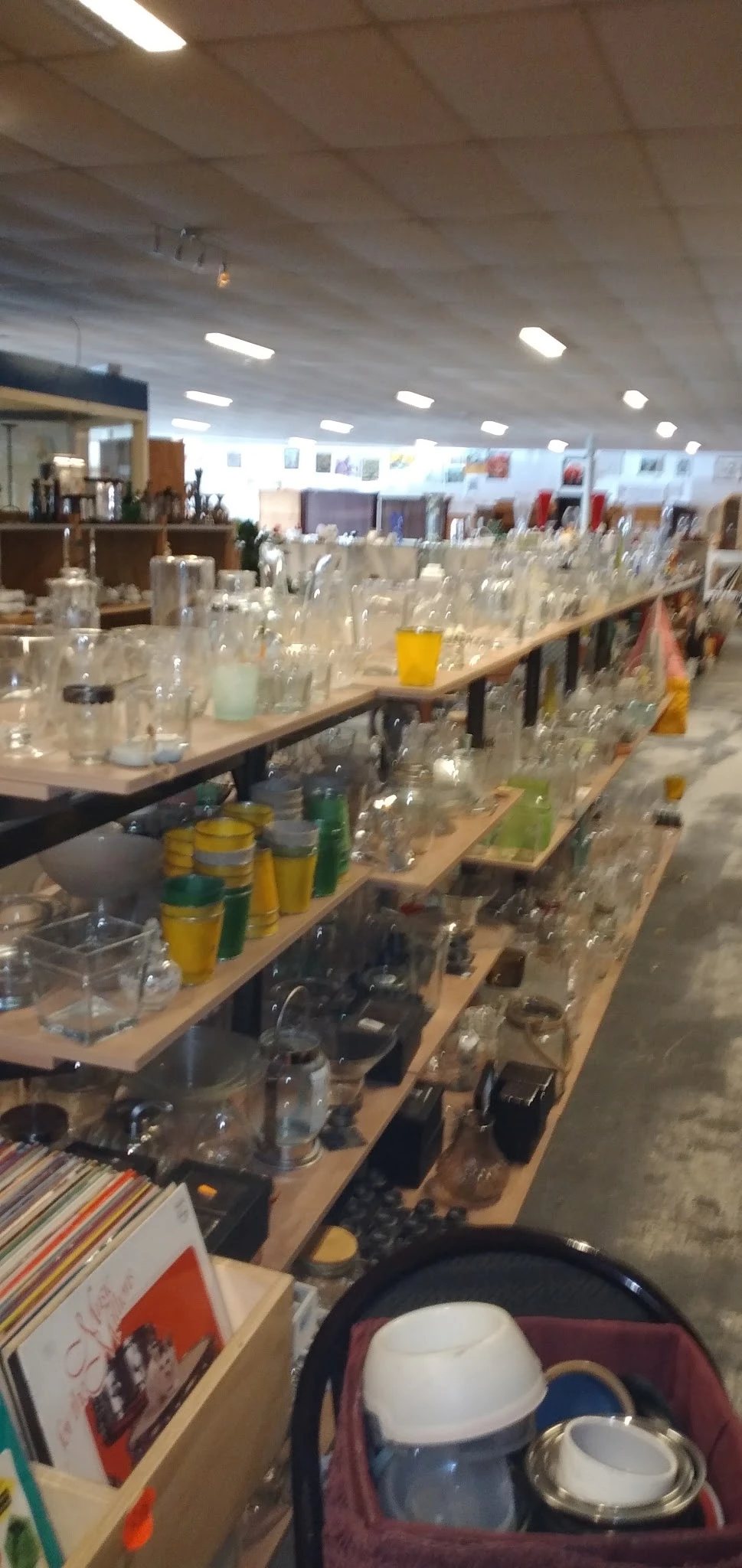 Lange werkbank met veel glazen flessen en potjes, waarschijnlijk huishoudelijke artikelen of decoratiestukken