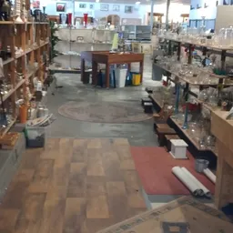 Overzicht van de winkelvloer met stellingen vol spullen, verschillende vloersoorten en uitgestalde artikelen