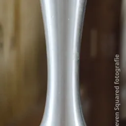 Close-up van een metallic zilverkleurig object met een gebogen vorm