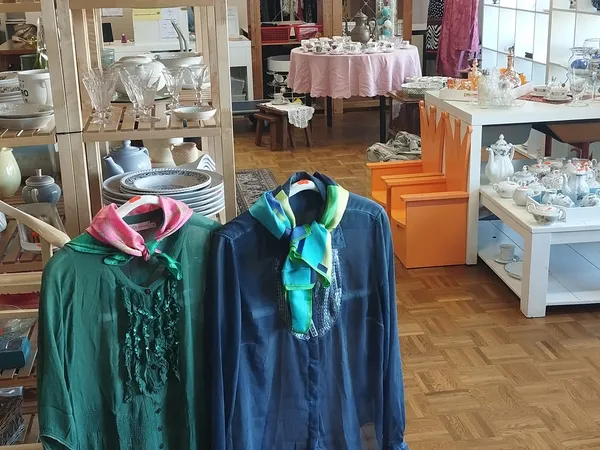 Winkelinterieur met kledingrek, serviesgoed in vitrine en decoratieve artikelen
