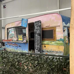 Binnenkant van een vintage caravan met beschilderde wanden, een servicebar en ramen met kunstwerk