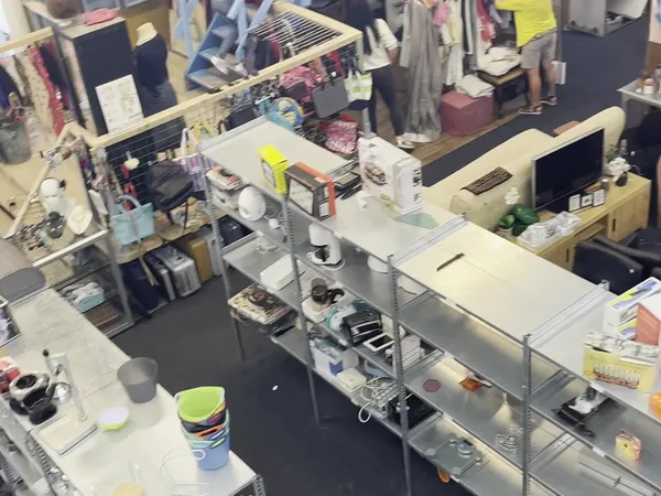 Overzicht van een kringloopwinkel met toonbanken, stellingen en diverse spullen