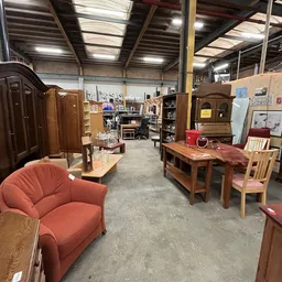 Magazijnruimte met houten meubels, rode stoelen, kasten en diverse tweedehandsspullen
