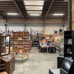 Ruim magazijnachtig interieur van kringloopwinkel met diverse meubels, boekenkasten, kasten en huishoudelijke items uitgestal