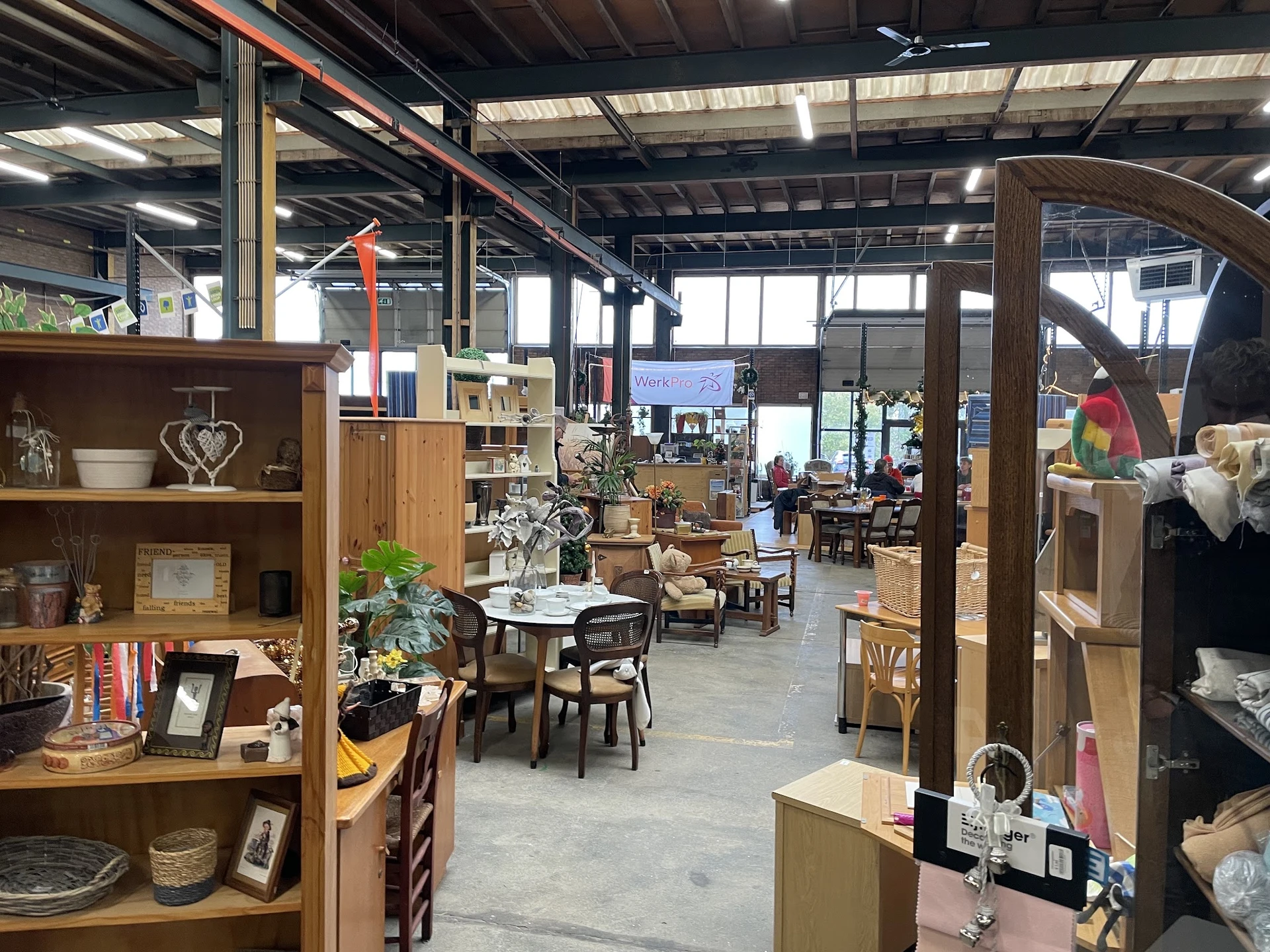 Winkelvloer met houten stellingen, meubels, decoratie en diversen in een ruime, lichte industriële ruimte