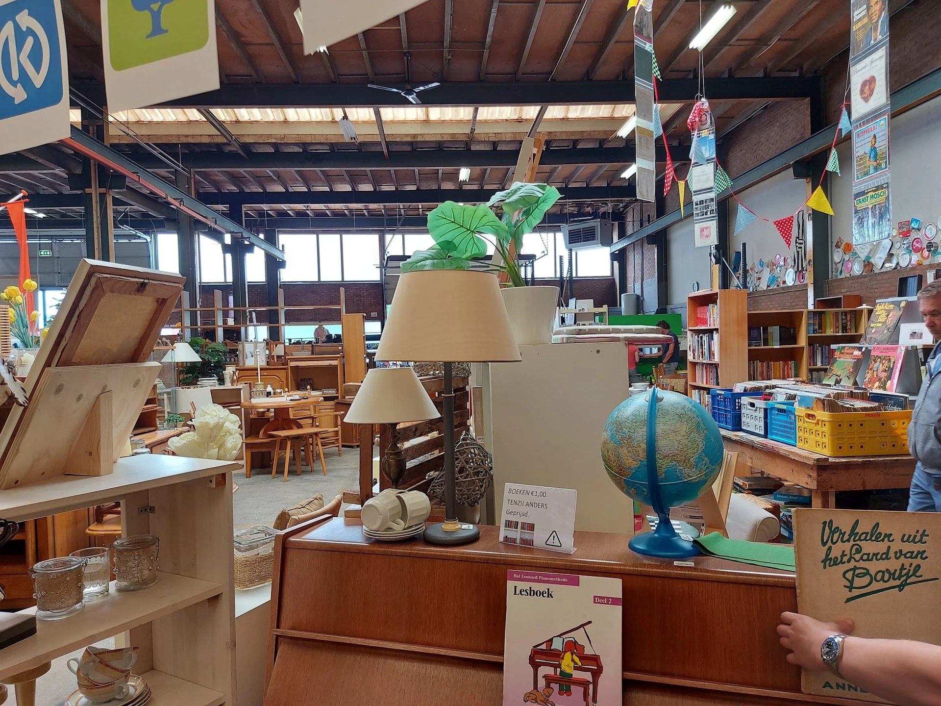 Winkelvloer met tafels, lampen, een wereldbol, boeken en diverse huishoudartikelen uitgestald
