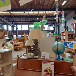 Winkelvloer met tafels, lampen, een wereldbol, boeken en diverse huishoudartikelen uitgestald