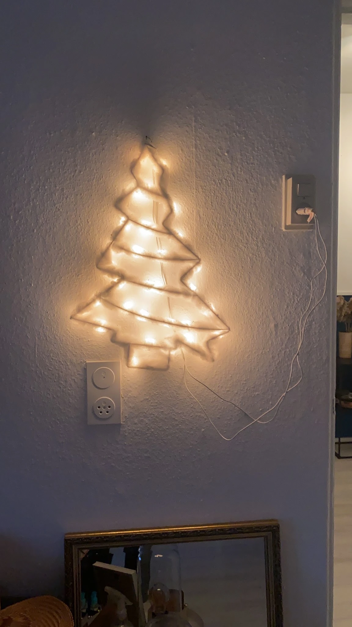 Decoratieve kerstboom gemaakt van warmwitte LED-lichtsnoer op een witte muur