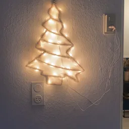 Decoratieve kerstboom gemaakt van warmwitte LED-lichtsnoer op een witte muur