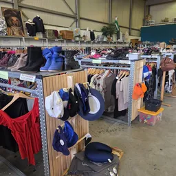 Overzicht van de winkelvloer met rekken vol kleding, schoenen en accessoires uitgestald op houten stellingen