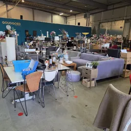 Winkelvloer met diverse meubels, stoelen, tafels en textiel uitgestald in een grote loods