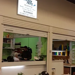 Binnenaanzicht van een kringloopwinkel met groene wanden, stellingen en een persoon achter de balie