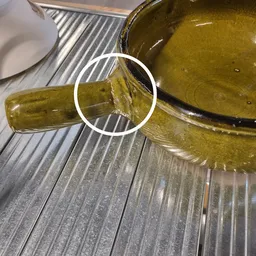 Close-up van een groene glazen fles met inhoud op een gestreepte ondergrond