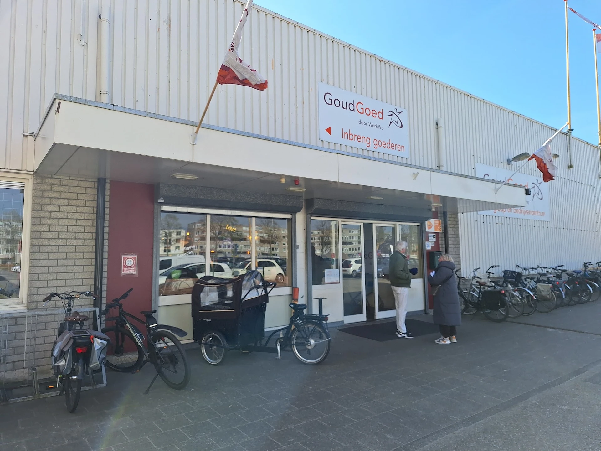 Voorgevel van kringloopwinkel GoudGoed met ingang, etalageruiten en fietsen ervoor