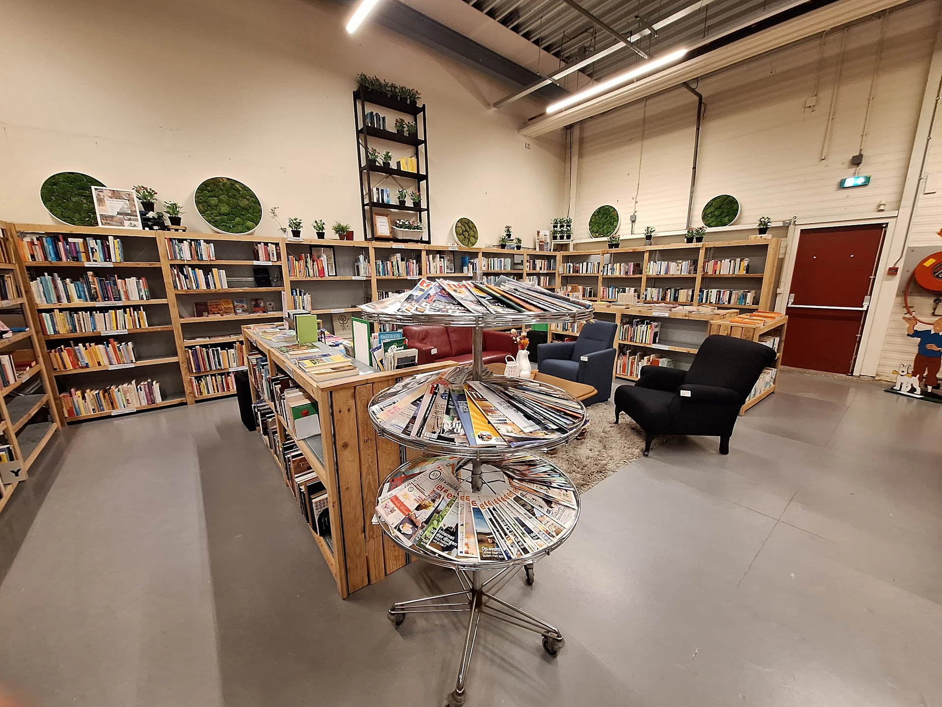 Winkelvloer met boekenkasten langs de wanden, draaiende boekenstellers in het midden, fauteuils en groene decoratieve bollen.