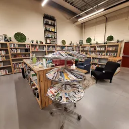 Winkelvloer met boekenkasten langs de wanden, draaiende boekenstellers in het midden, fauteuils en groene decoratieve bollen.