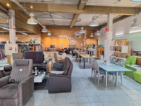 Winkelvloer met zithoeken, meubels en stellingen vol spullen in een kringloopwinkel