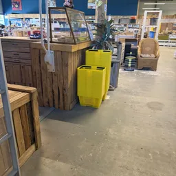 Winkelvloer met houten kastjes en gele plastic manden tussen ander winkelmateriaal