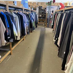 Winkelpad tussen rekken met opgehangen kleding in verschillende kleuren