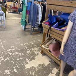Winkelinterieur met kledinrekken, stellingen met diverse artikelen en dozen met spullen op de vloer