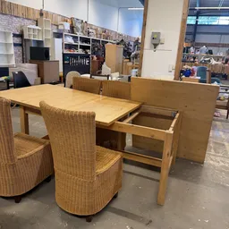 Houten eettafel met uitschuifblad en rattan stoelen in kringloopwinkel