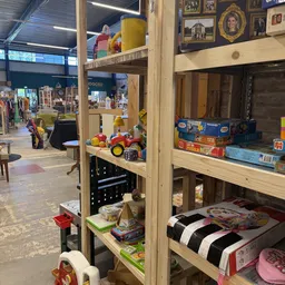 Houten stellingkast met speelgoed, kindermeubels en diverse huishoudspullen in de kringloopwinkel