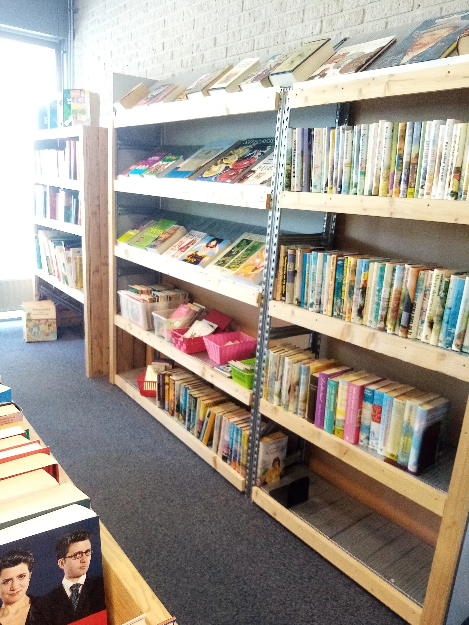Stellingen met uitgestalde boeken, dvd's en cd's in verschillende kleuren en formaten