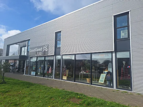 Moderne gevel van kringloopwinkel GoudGoed met grote raampartijen en zichtbare etalage, witte golfplaten bekleding