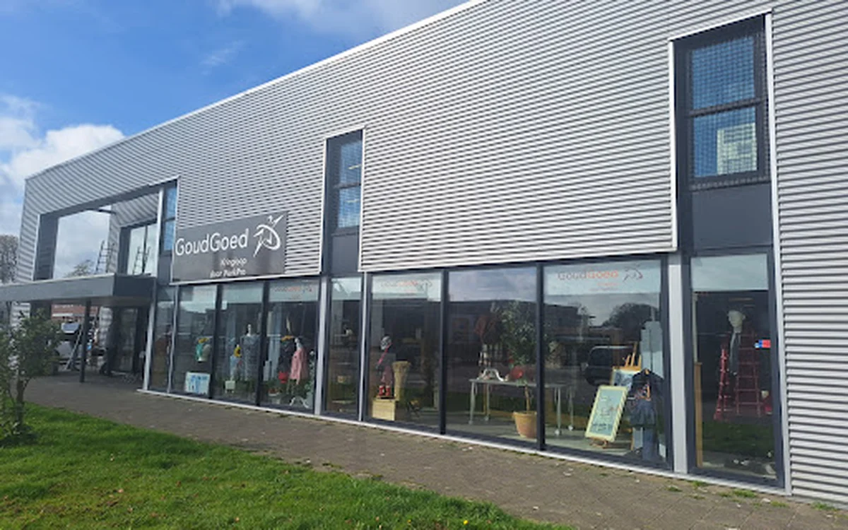 Moderne gevel van kringloopwinkel GoudGoed met grote raampartijen en zichtbare etalage, witte golfplaten bekleding