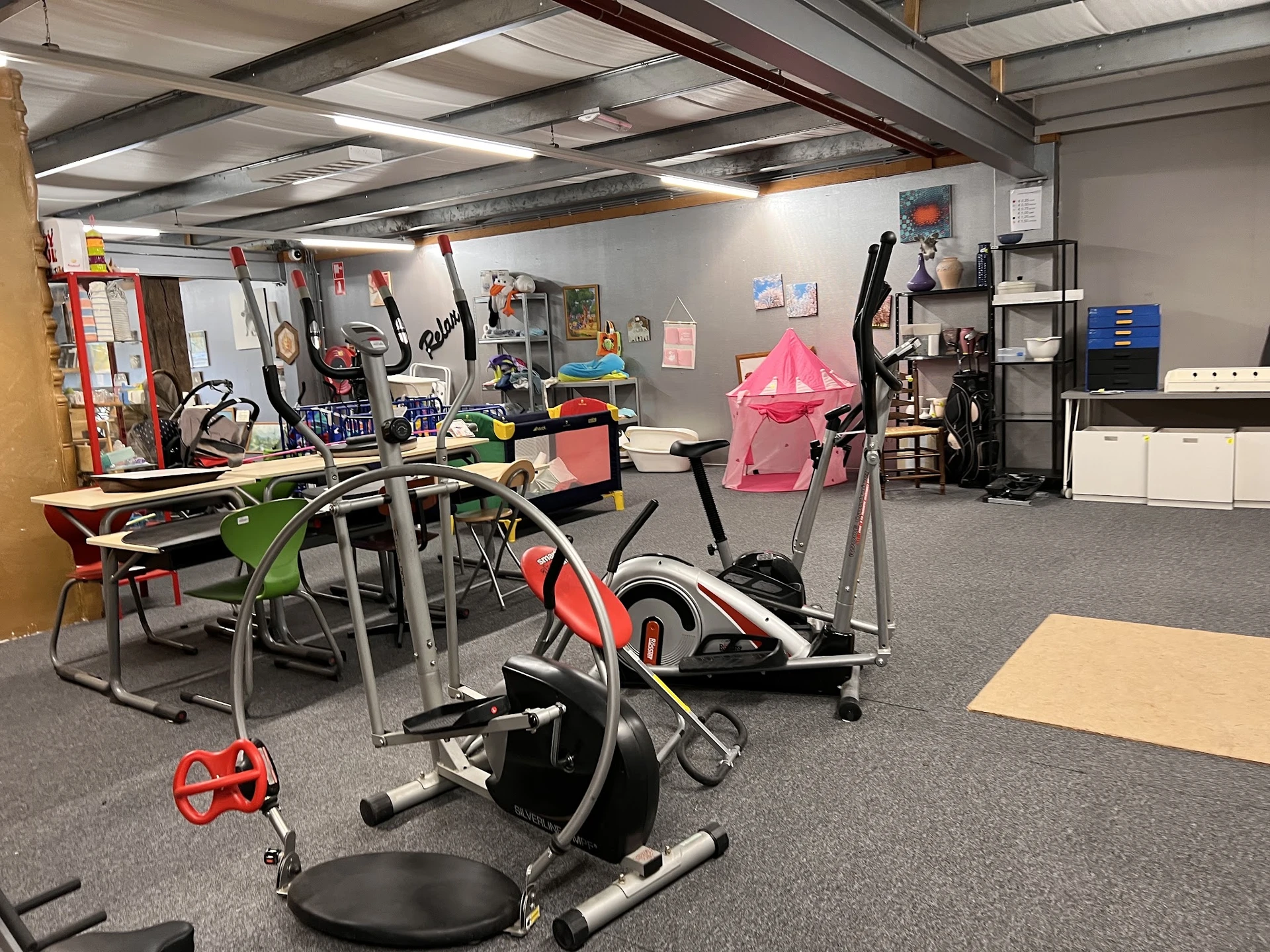 Winkelvloer met hometrainers, fitnessapparatuur en diverse spullen op stellingen