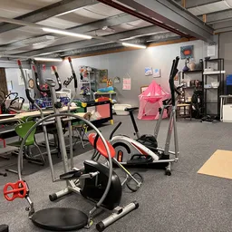 Winkelvloer met hometrainers, fitnessapparatuur en diverse spullen op stellingen