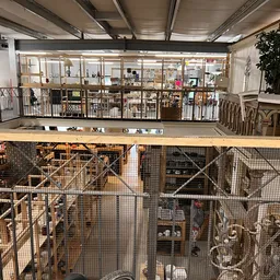 Tweelaags kringloopwinkel met geafschermde opslagruimtes, stellingen en diverse goederen zichtbaar