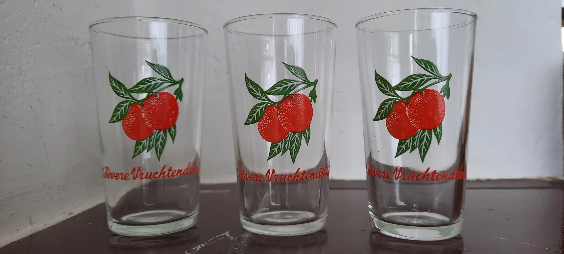 Drie glazen met rode tomaten en groene bladeren op het etiket