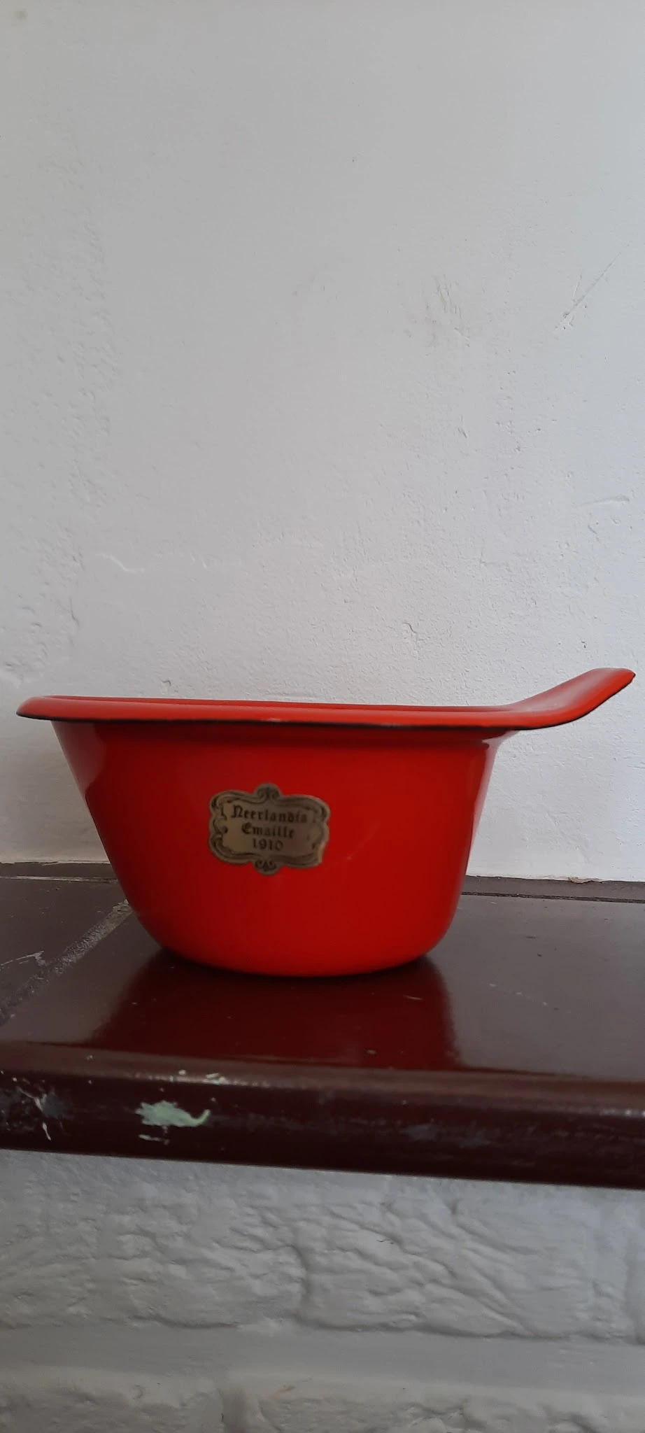 Rode emaille braadpan met handvat en vintage merkplaatje, tegen witte achtergrond
