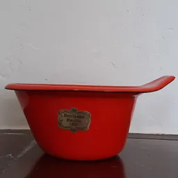 Rode emaille braadpan met handvat en vintage merkplaatje, tegen witte achtergrond