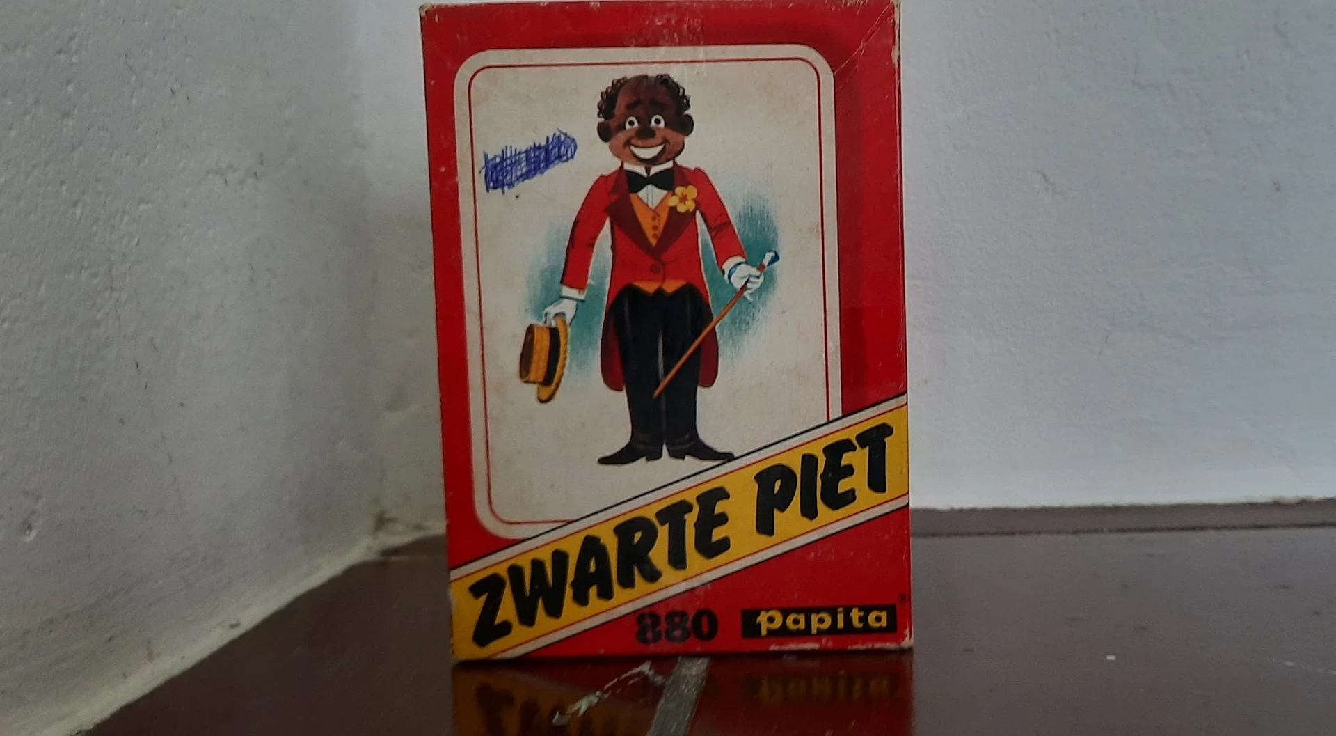 Vintage speelgoedverpakking van Zwarte Piet met figuur in rode jas en zwart pak