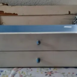 Wit nachtkastje met twee lades en blauwe knopjes