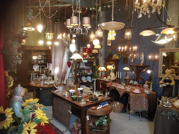 Winkelvloer met diverse hangende lampen, kroonluchters en uitgestalde decoratieve items op tafels