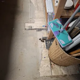 Betonnen vloer met diverse spullen langs de rand, waaronder een turquoise kist en houten items