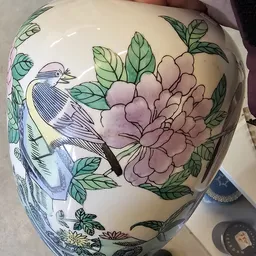 Close-up van een decoratief porseleinItem met handgeschilderde vogel en bloemendessin in pasteltinten