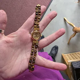 Goudkleurig dameshorloge met armband wordt in hand gehouden