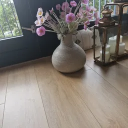 Witte gestructureerde vaas met roze en paarse bloemen op een houten vloer