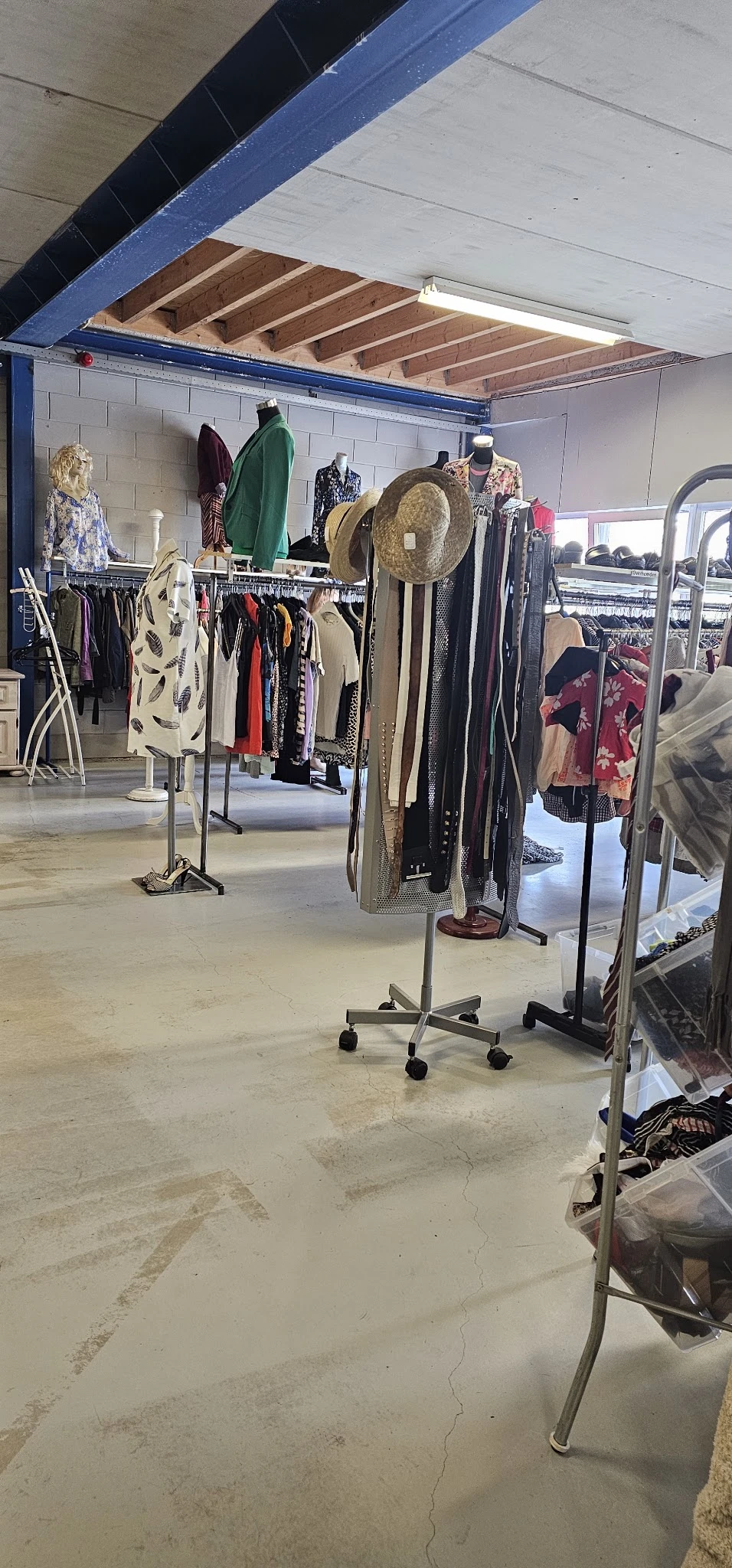 Rekken met tweedehands kleding en accessoires in de kringloopwinkel