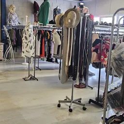 Rekken met tweedehands kleding en accessoires in de kringloopwinkel