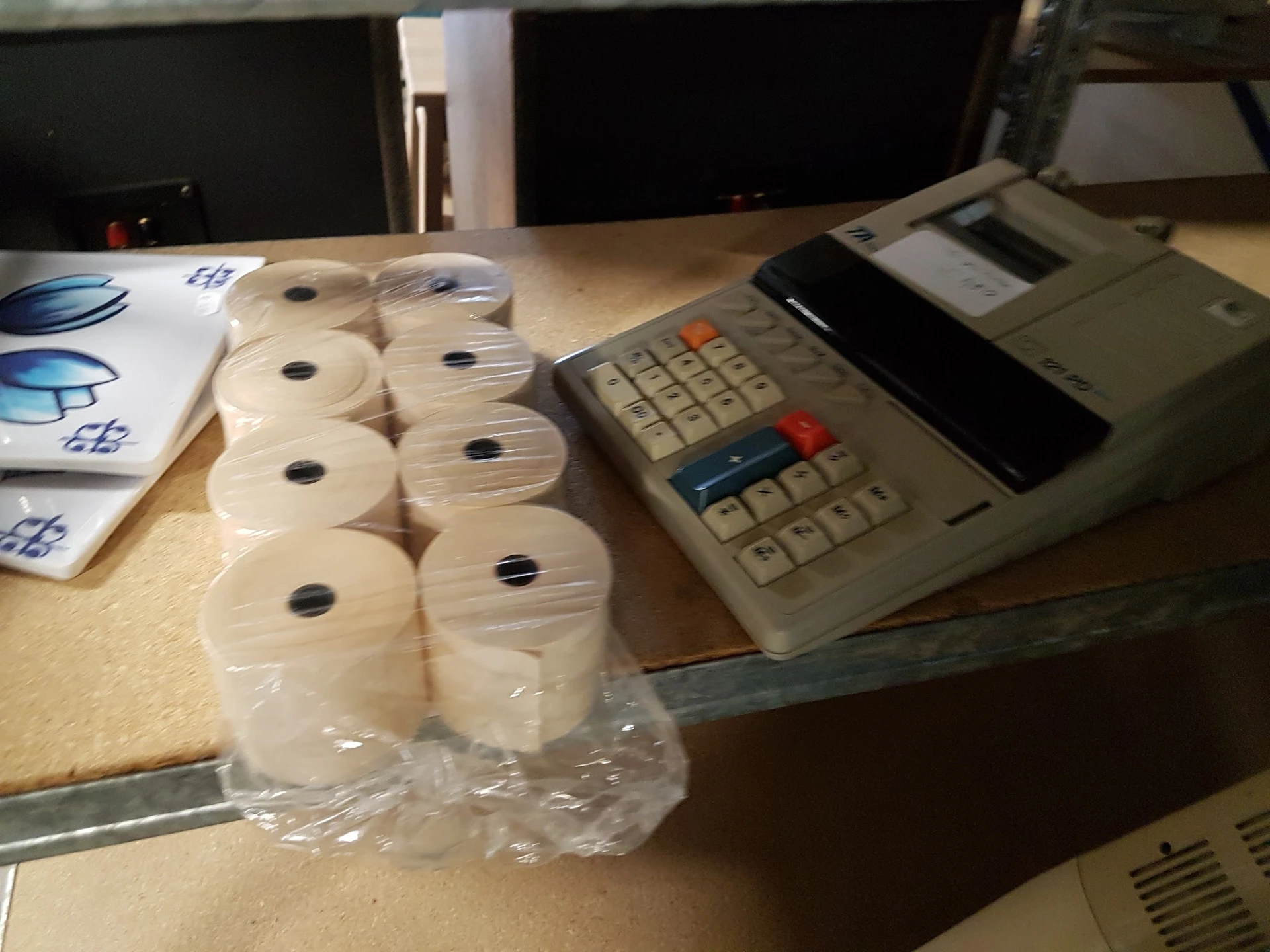 Rollen toiletpapier in kunststofverpakking naast een kasregister op een werkblad