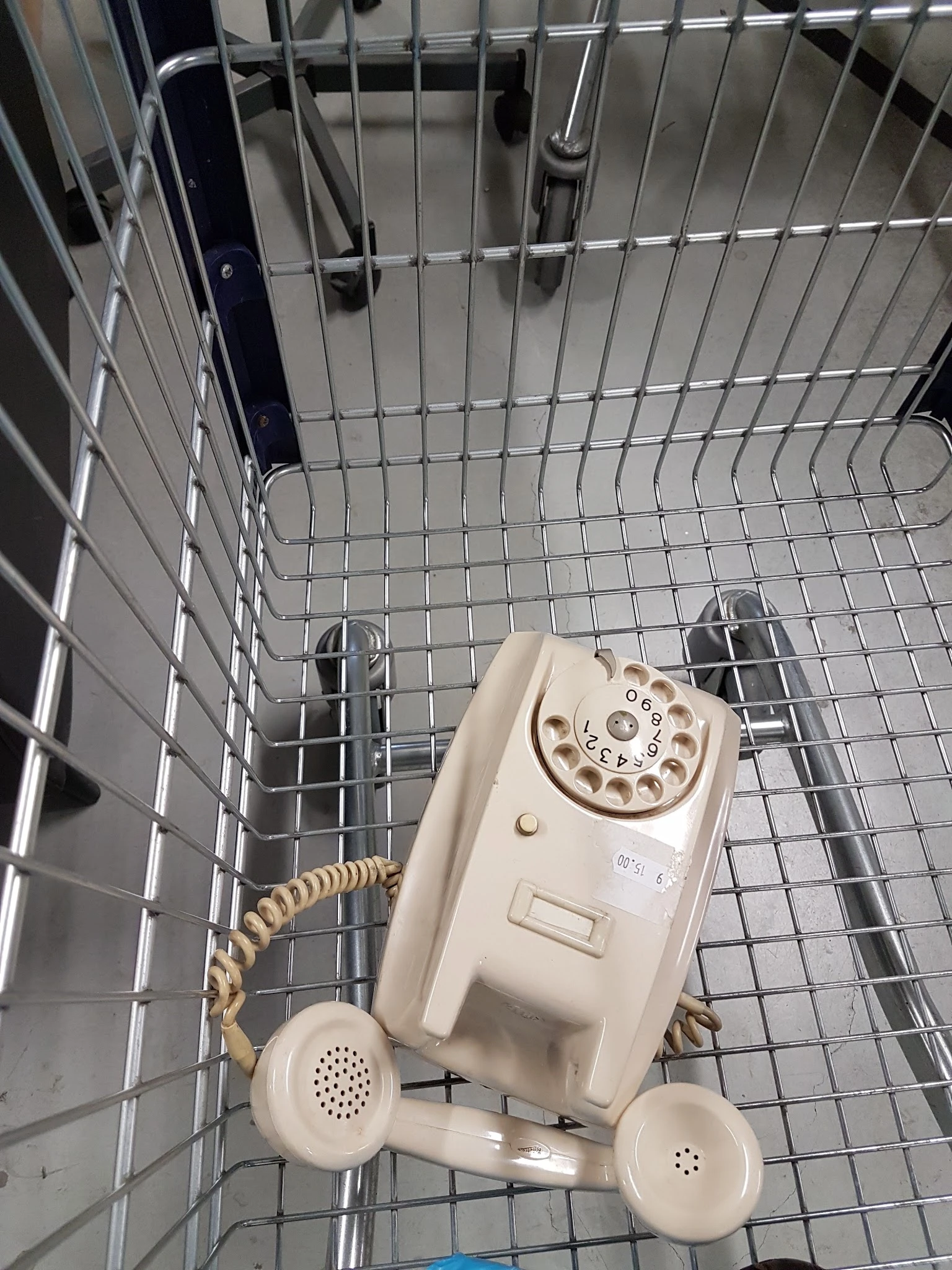 Vintage creme-kleurige draaischijftelefoon in een winkelkrat