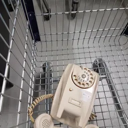Vintage creme-kleurige draaischijftelefoon in een winkelkrat