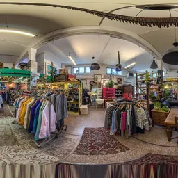 Ruim interieur van kringloopwinkel met kledingrekken, meubels en diverse artikelen onder bolgewelf